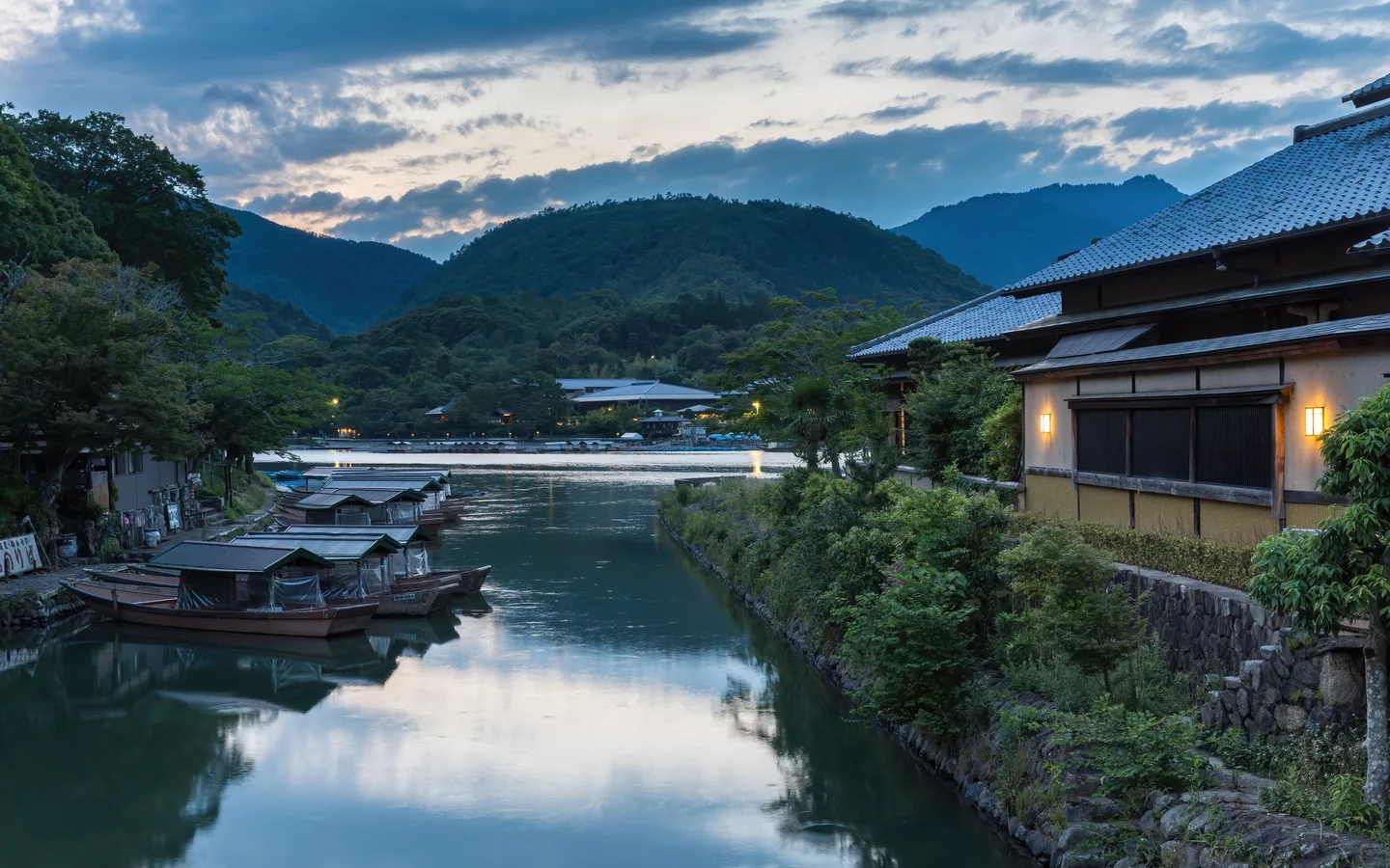Katsura River bank with pleasure boats and illuminated building at sunset Kyoto Japan.jpg