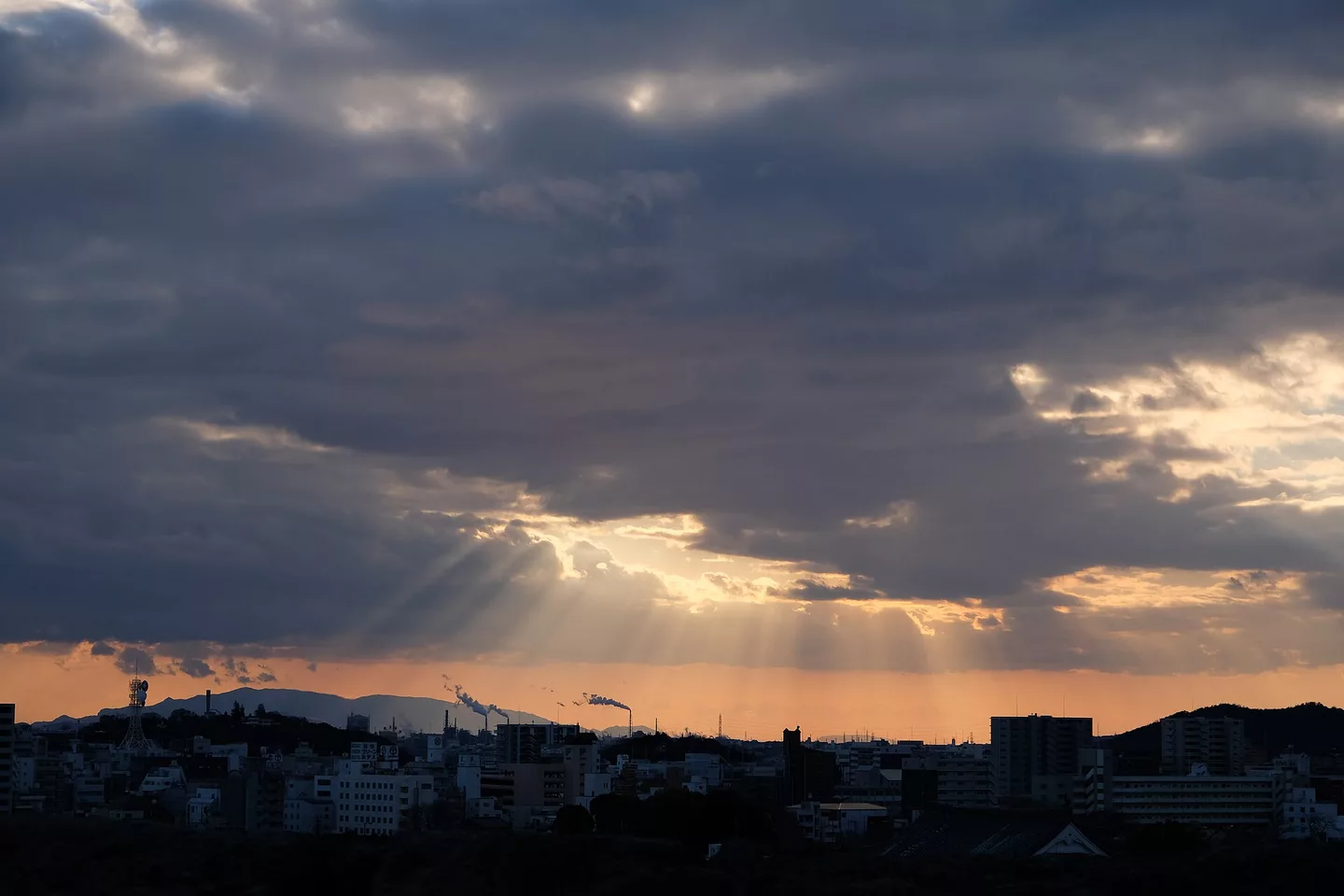 Crepuscular rays over Himeji skyline smokestacks.jpg
